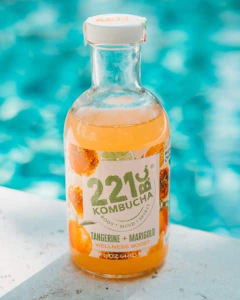 bottle of tangerine + marigold kombucha flavor by pool